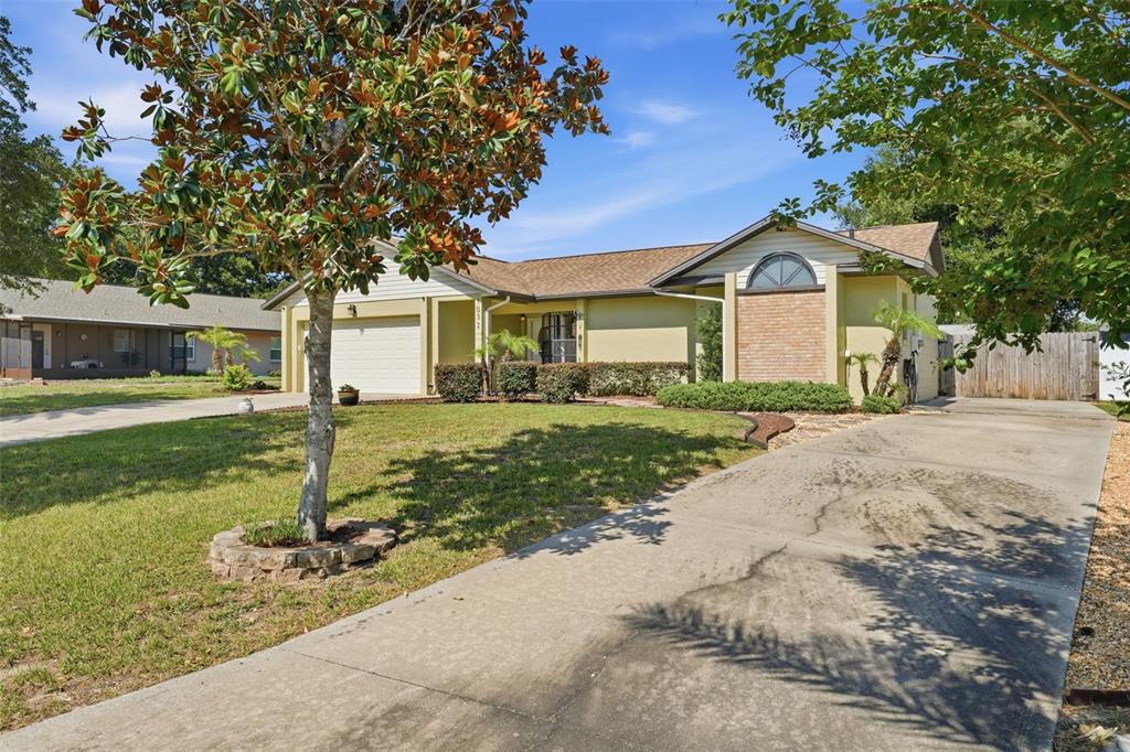 A single-story house with a beige exterior, brick accent wall, and a concrete driveway — 103 RIDGECREST DRIVE, EUSTIS, FL