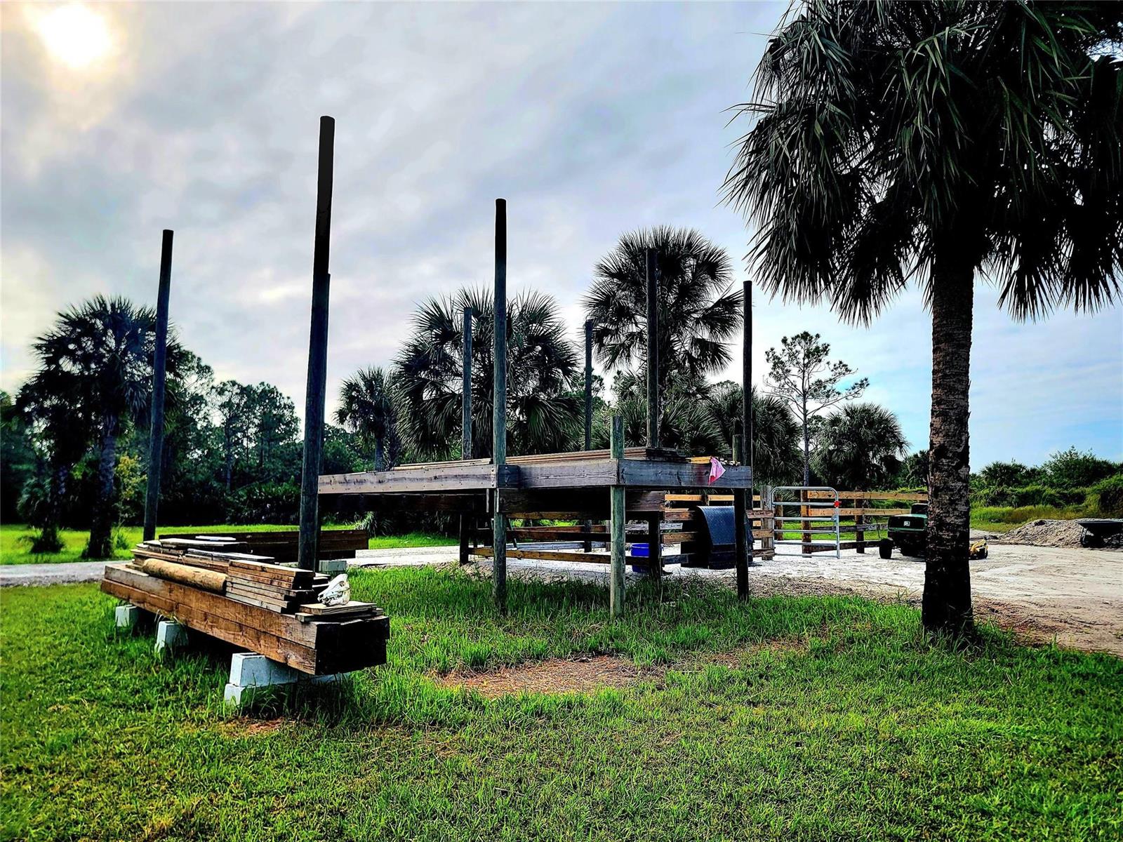 An outdoor wooden platform structure stands in a grassy field with palm trees and fencing — 15350 93rd Street, Fellsmere FL 32948, FELLSMERE, FL