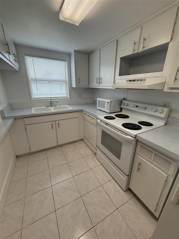 A kitchen with white cabinets, white appliances, a double sink, and light-colored tile flooring — 7701 STARKEY ROAD UNIT 239, SEMINOLE, FL