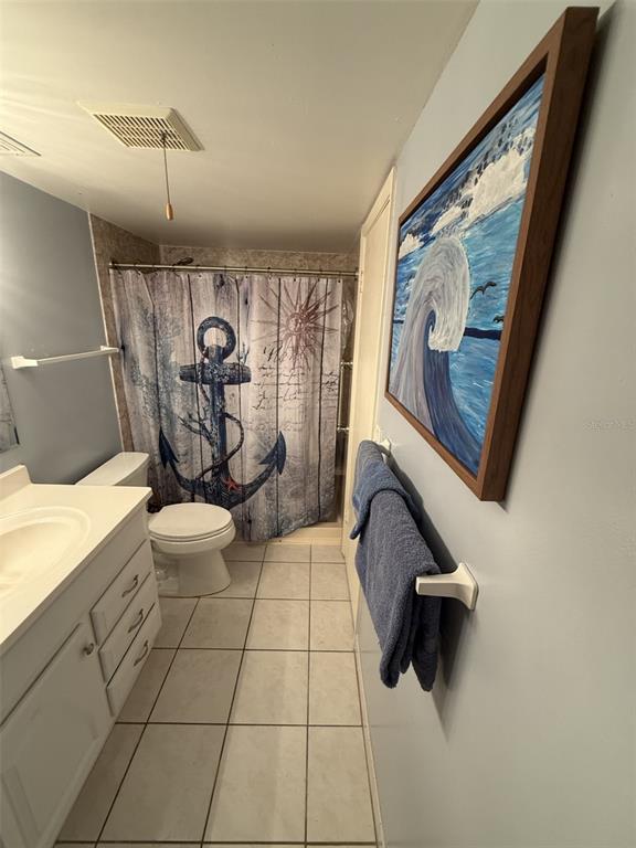 A bathroom features a nautical-themed shower curtain, a white vanity, and a wave painting — 7701 STARKEY ROAD UNIT 239, SEMINOLE, FL