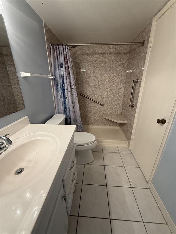 A bathroom features a white vanity, a toilet, and a walk-in shower with grab bars — 7701 STARKEY ROAD UNIT 239, SEMINOLE, FL