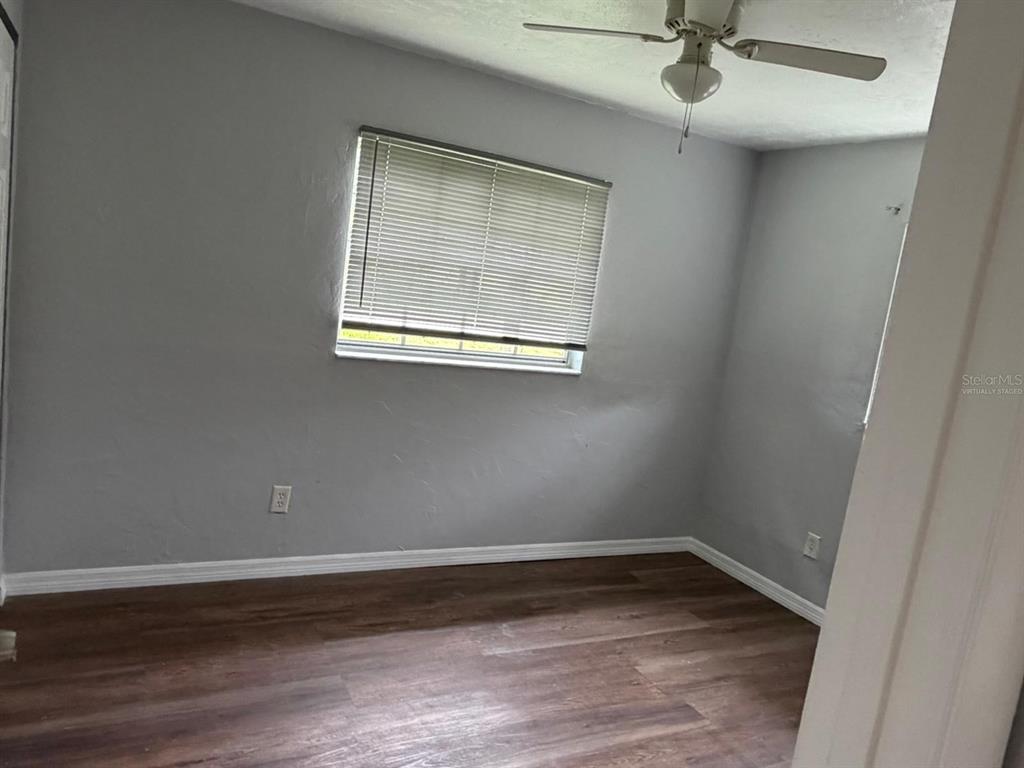 An empty bedroom features gray walls, wood-look flooring, a ceiling fan, and a window with blinds — 1423 NE LIVINGSTON STREET, ARCADIA, FL