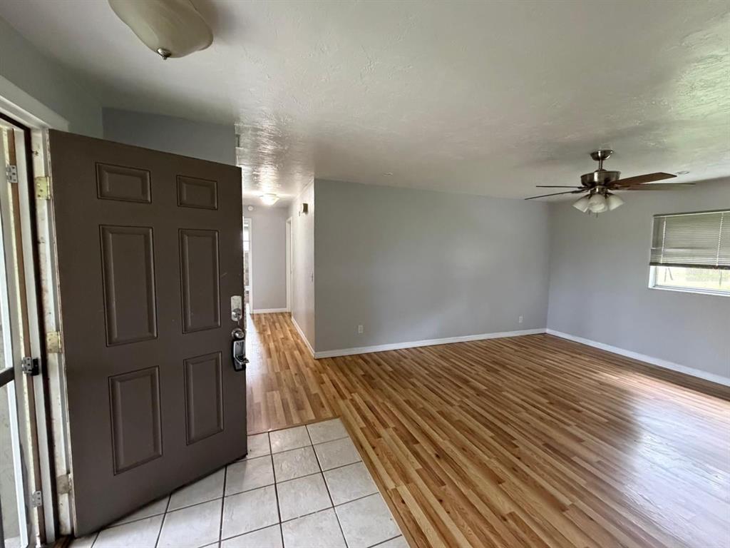 An entryway with tile flooring leads into a living room featuring wood-look floors and a fan — 1423 NE LIVINGSTON STREET, ARCADIA, FL