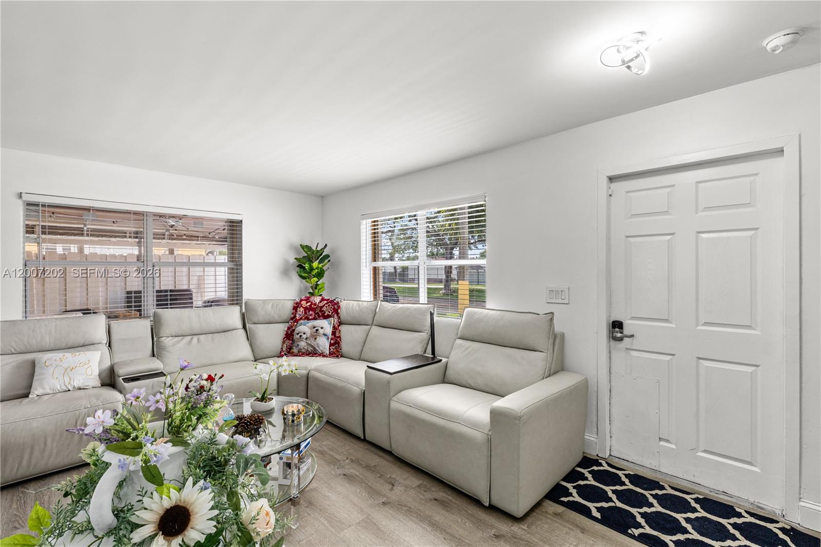 A living room features a light-colored sectional sofa, a glass coffee table, and a white door — 203 NE 12th Ave # 203, Homestead FL 33030, HOMESTEAD, FL
