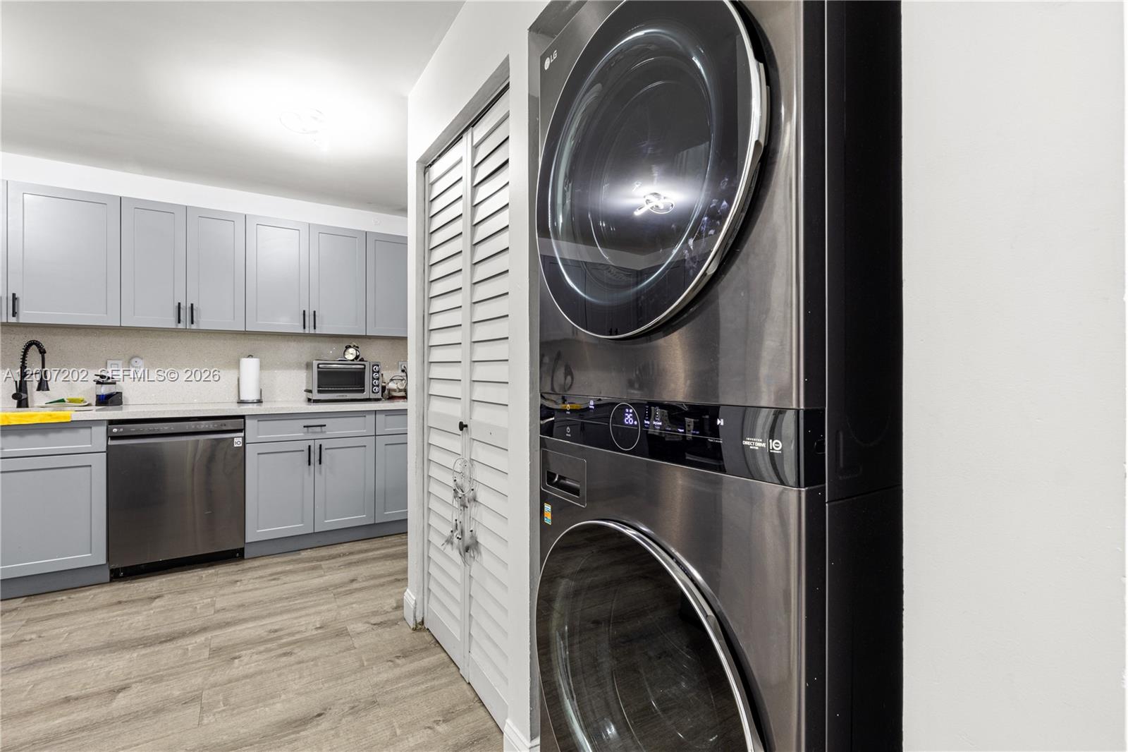 A kitchen with gray cabinets and stainless steel appliances sits beside a stacked laundry unit — 203 NE 12th Ave # 203, Homestead FL 33030, HOMESTEAD, FL
