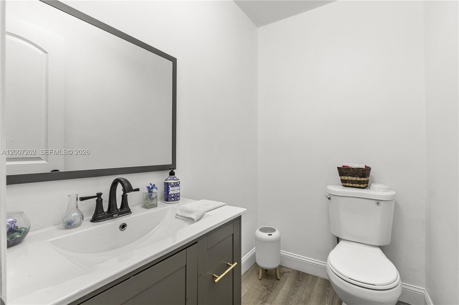 A bathroom features a gray vanity with a dark faucet, a mirror, and a toilet — 203 NE 12th Ave # 203, Homestead FL 33030, HOMESTEAD, FL