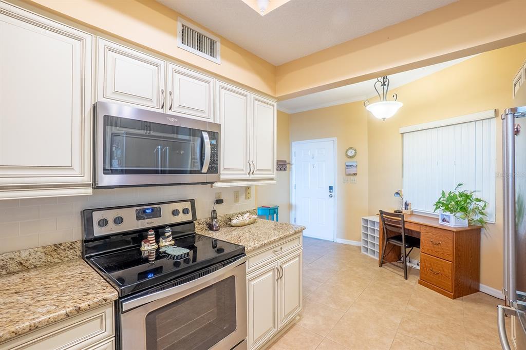 A kitchen with a small desk area, stainless steel appliances, and light-colored cabinetry — 104 SURFVIEW DRIVE UNIT 2204, PALM COAST, FL