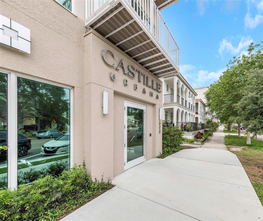 The exterior of a beige building features a glass entrance door and a metal balcony — 600 3RD AVENUE S UNIT 305, ST PETERSBURG, FL