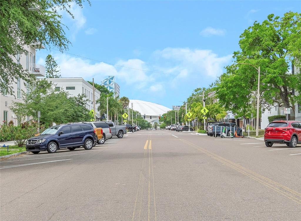 A street view shows parked cars along both sides of a road leading toward a stadium — 600 3RD AVENUE S UNIT 305, ST PETERSBURG, FL