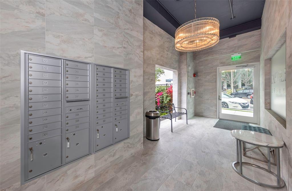 A mailroom features marble-tiled walls, a crystal chandelier, and a glass door leading outside — 600 3RD AVENUE S UNIT 305, ST PETERSBURG, FL