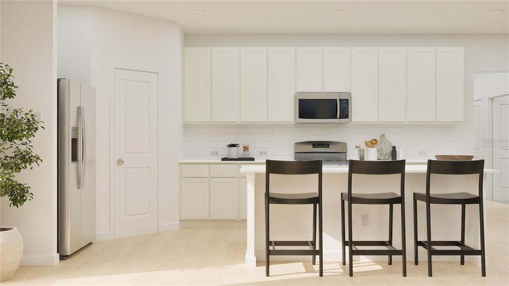 A modern kitchen features white cabinetry, a stainless steel microwave, and a breakfast bar island — 3063 REPOSE DRIVE, CLERMONT, FL