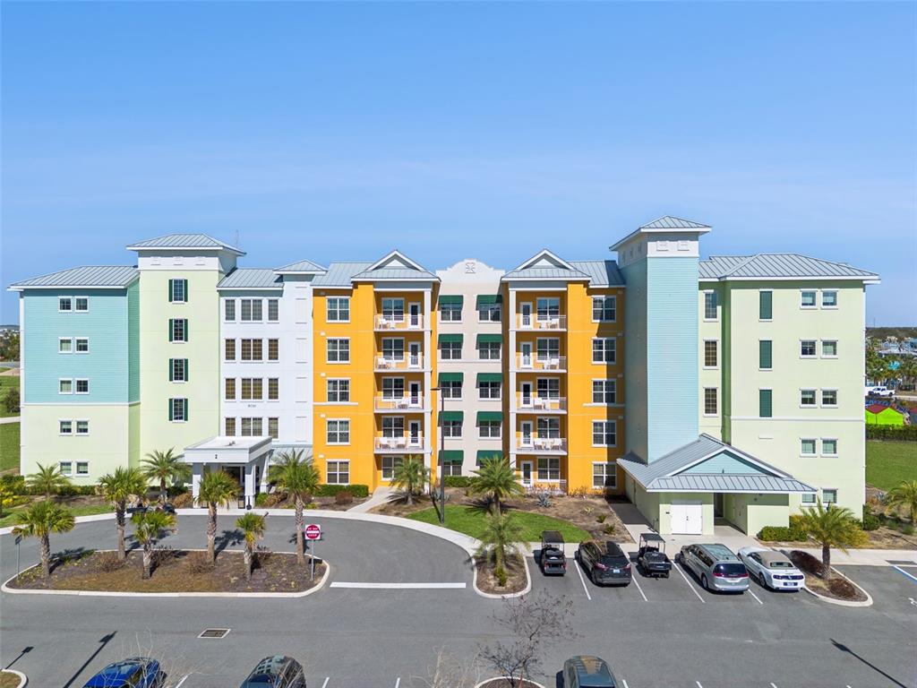 A multi-story apartment building with colorful exterior walls and a parking lot in front — 8061 VACATION AVENUE UNIT 2510, KISSIMMEE, FL