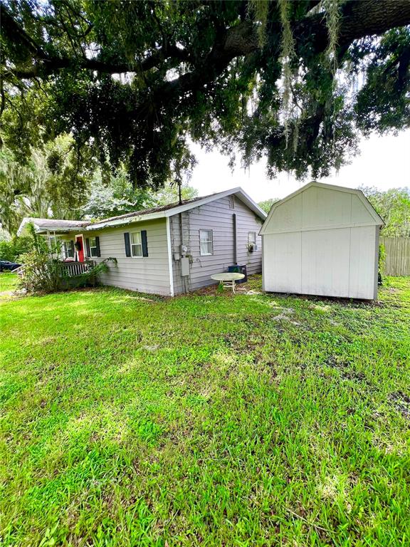 A gray house with a porch and a white shed sit on a grassy lot — 1008 GRAY STREET, PLANT CITY, FL
