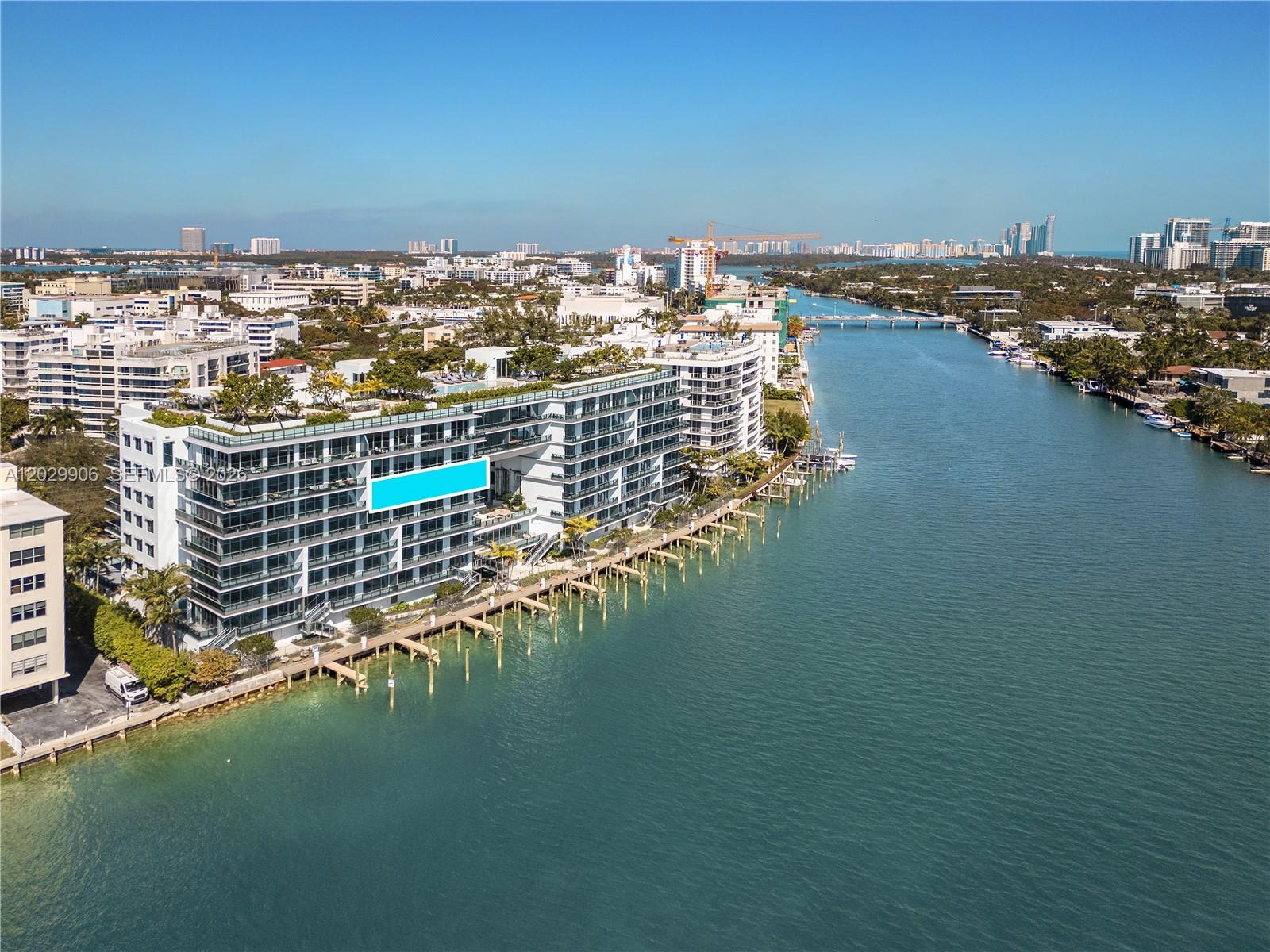 An aerial view shows a modern waterfront apartment building with a balcony and boat docks — 9201 E Bay Harbor Dr # 603, Bay Harbor Islands FL 33154, BAY HARBOR ISLANDS, FL