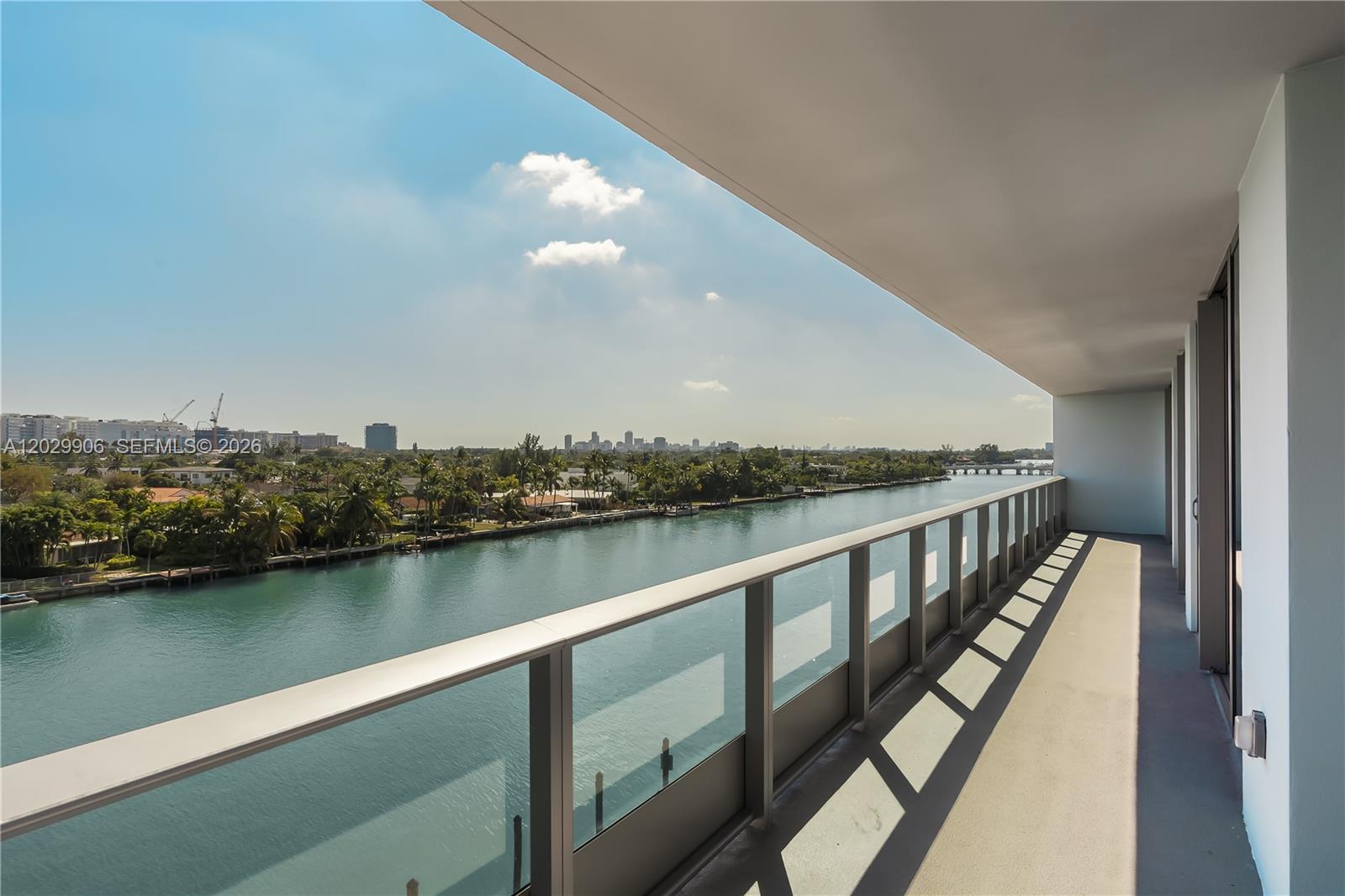 A balcony with a glass railing overlooks a canal and a distant city skyline — 9201 E Bay Harbor Dr # 603, Bay Harbor Islands FL 33154, BAY HARBOR ISLANDS, FL