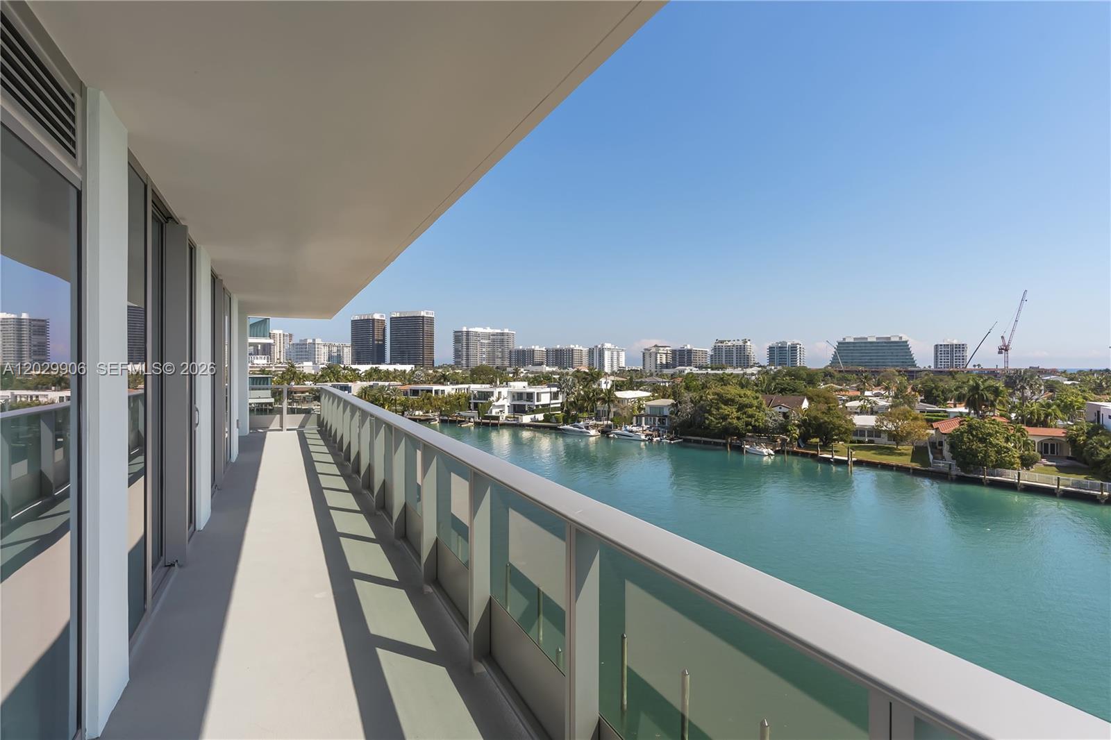 A balcony with a glass railing overlooks a canal and a city skyline — 9201 E Bay Harbor Dr # 603, Bay Harbor Islands FL 33154, BAY HARBOR ISLANDS, FL
