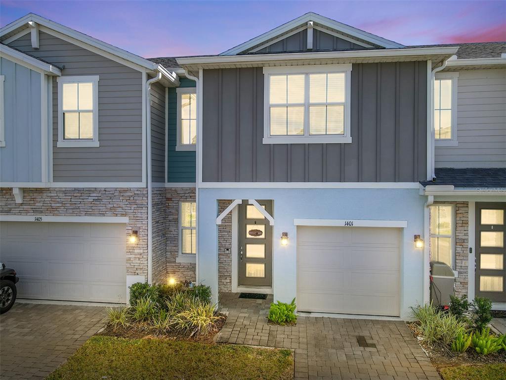 A two-story townhouse exterior features gray siding, stone accents, and two attached garages — 1401 CAPTIVA COVE UNIT 23, SANFORD, FL