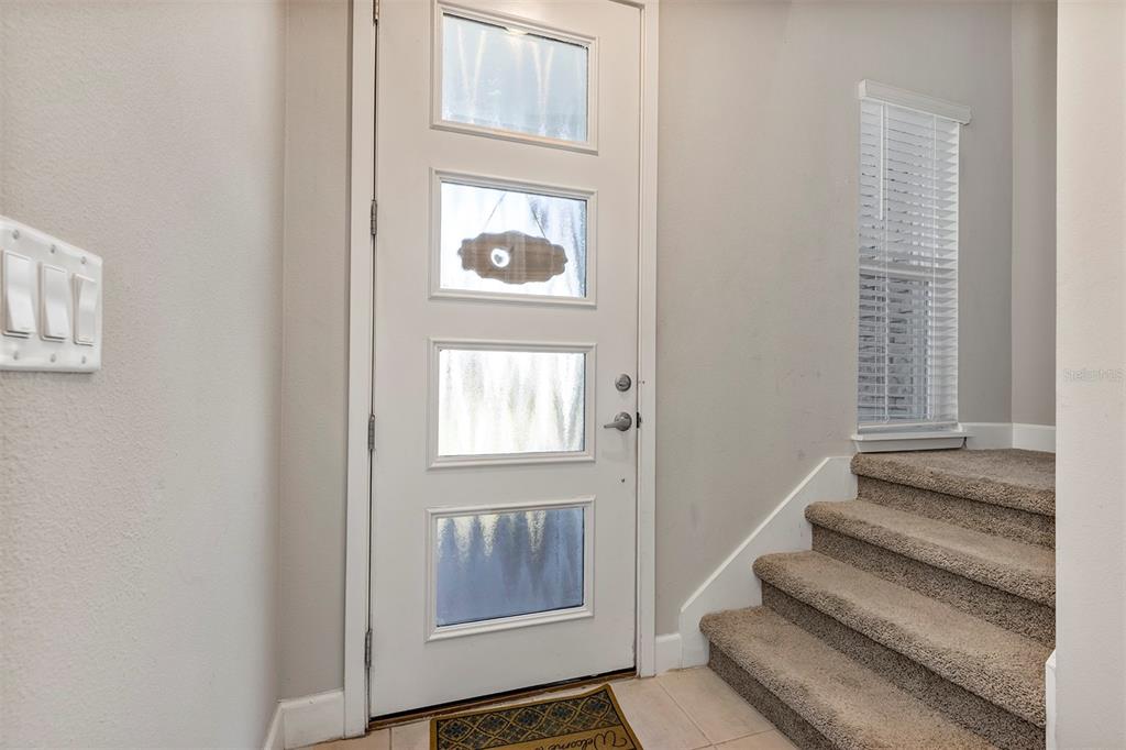 An entryway features a white front door with four glass panels and carpeted stairs — 1401 CAPTIVA COVE UNIT 23, SANFORD, FL