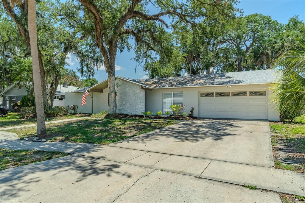 A single-story house with a stone facade and a large tree in the front yard — 8018 W POCAHONTAS AVENUE, TAMPA, FL