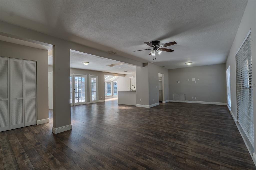A kitchen features white cabinets, stainless steel appliances, granite countertops, and wood-look flooring — 8018 W POCAHONTAS AVENUE, TAMPA, FL