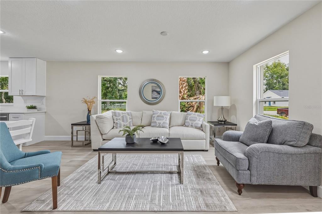 A living room features a white sofa, gray loveseat, blue armchair, and a coffee table — 312 ALBANY AVENUE, DELAND, FL