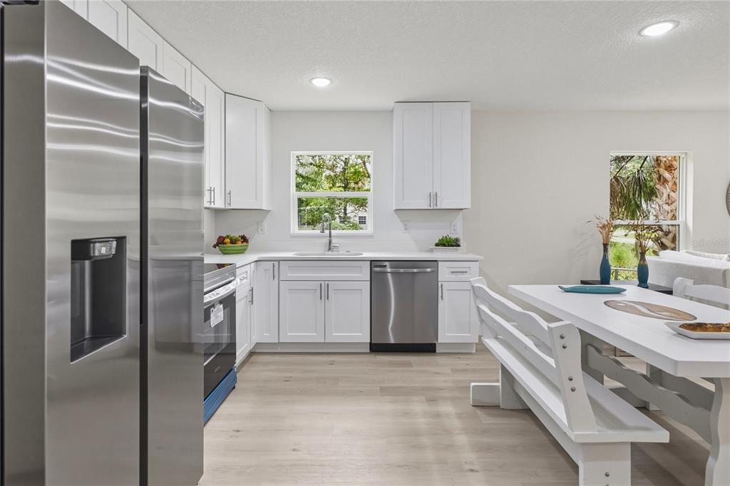 A modern kitchen features white cabinets, stainless steel appliances, and a dining table with benches — 312 ALBANY AVENUE, DELAND, FL