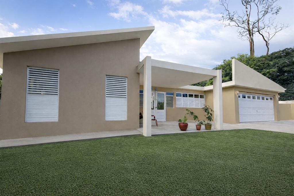 A modern, tan-colored single-story house with a flat roof, white shutters, and a covered patio — Carr 793 KM 1.2 QUINTAS DE JAGUEYES 31A, AGUAS BUENAS, PR