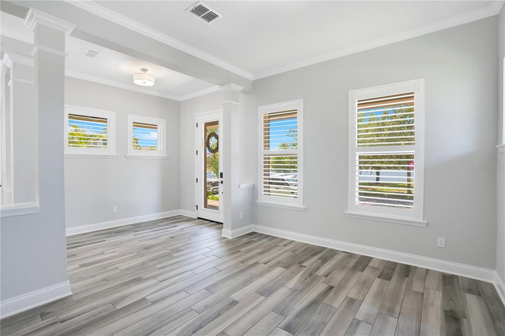 A bright dining area features light wood-look tile floors, a modern pendant light, and glass doors — 13101 GABOR AVENUE, ORLANDO, FL