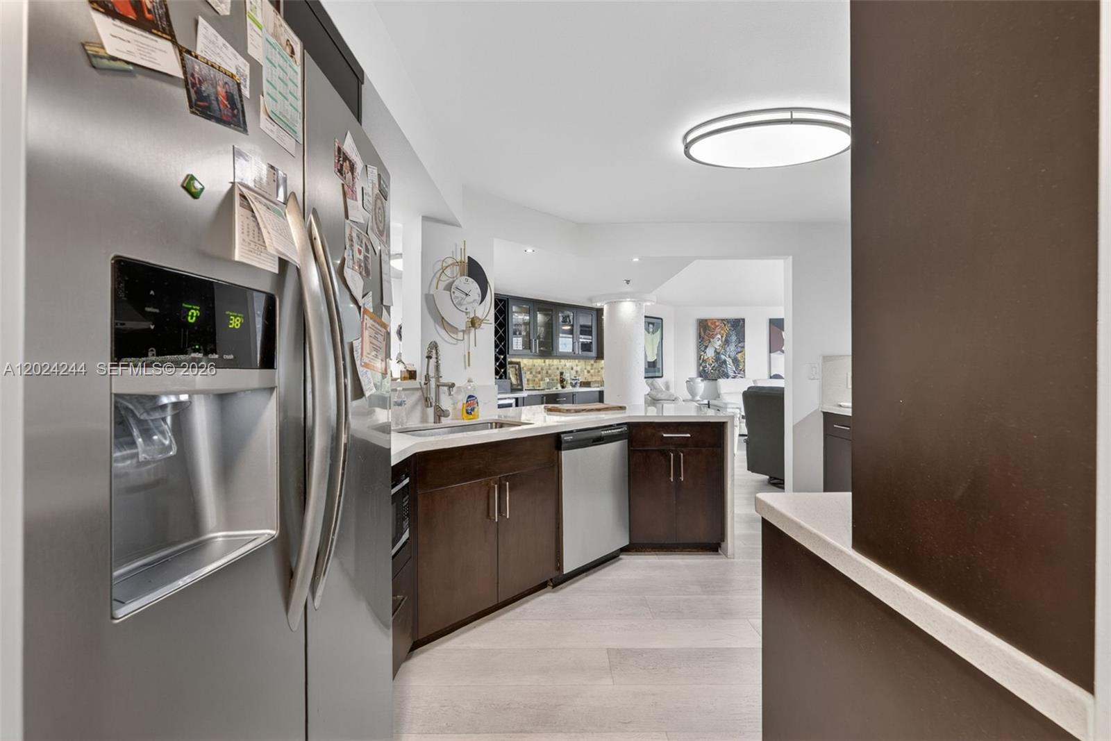 A modern kitchen features dark wood cabinets, stainless steel appliances, and light-colored flooring — 300 Three Islands Blvd # 710, Hallandale Beach FL 33009, HALLANDALE BEACH, FL