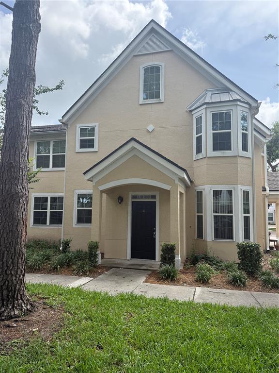 A two-story tan stucco house features a covered entryway, a bay window, and a front lawn — 3392 WESTCHESTER SQUARE BOULEVARD UNIT 101, ORLANDO, FL