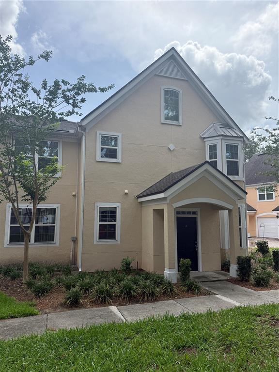 A two-story tan stucco townhouse with a dark front door and a covered entryway — 3392 WESTCHESTER SQUARE BOULEVARD UNIT 101, ORLANDO, FL