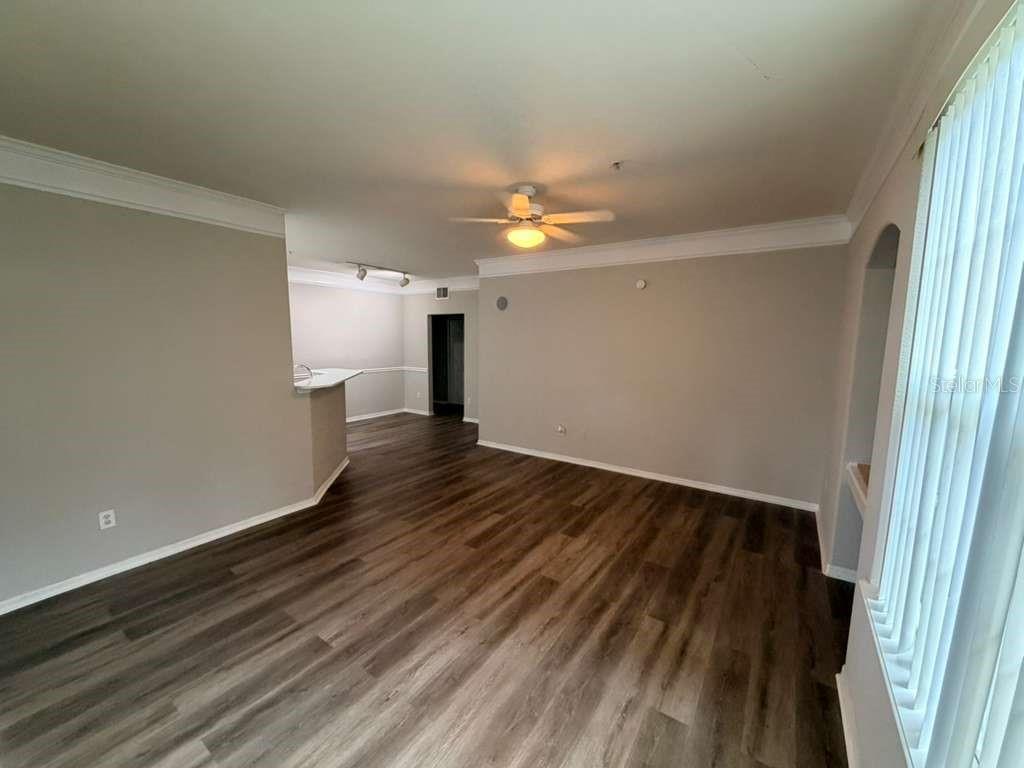An interior view of a living room with wood-look flooring, crown molding, and a ceiling fan — 3392 WESTCHESTER SQUARE BOULEVARD UNIT 101, ORLANDO, FL