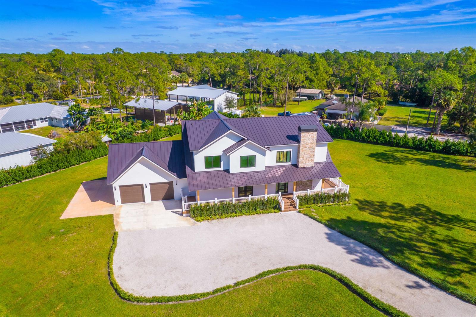 An aerial view shows a two-story white farmhouse with a dark metal roof and driveway — 13613 157th Court N, Jupiter FL 33478, JUPITER, FL