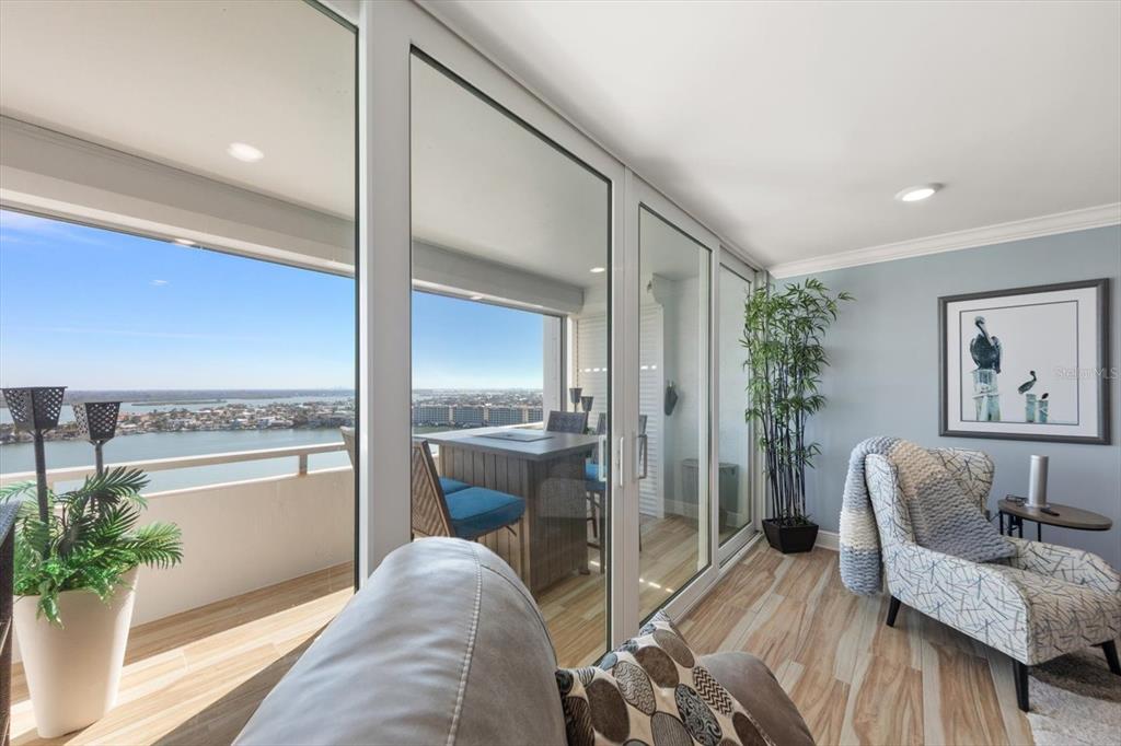 A living room with light wood floors and sliding glass doors opening to a balcony view — 17920 GULF BOULEVARD UNIT 1901, REDINGTON SHORES, FL