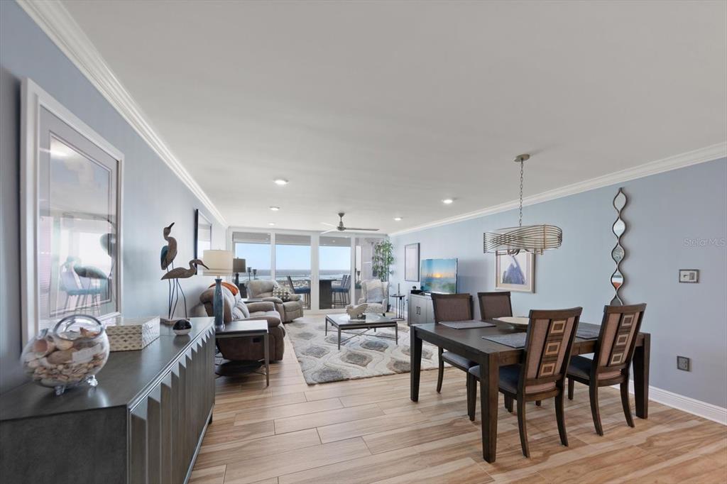 An open-concept living and dining area features light blue walls, wood-look tile flooring, and balcony views — 17920 GULF BOULEVARD UNIT 1901, REDINGTON SHORES, FL