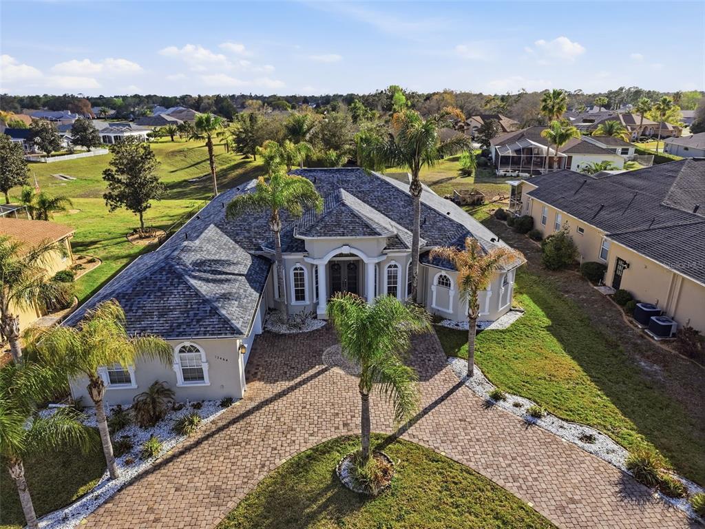 An aerial view shows a single-story house with a paved circular driveway and palm trees — 13464 SATINWOOD COURT, SPRING HILL, FL