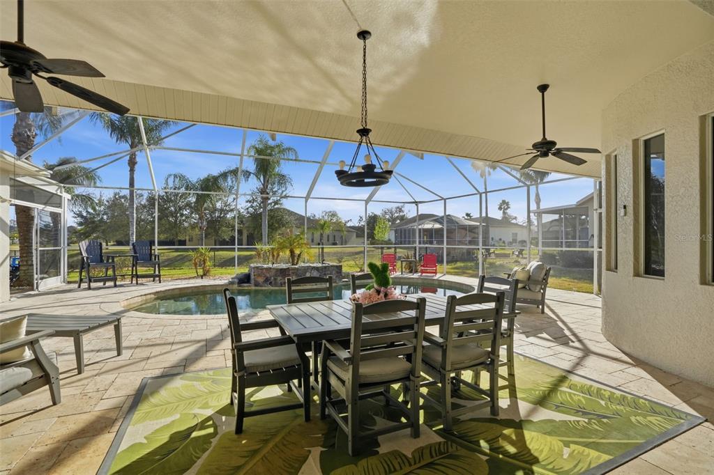 A covered patio features a dining set, a swimming pool, and a screened-in enclosure — 13464 SATINWOOD COURT, SPRING HILL, FL