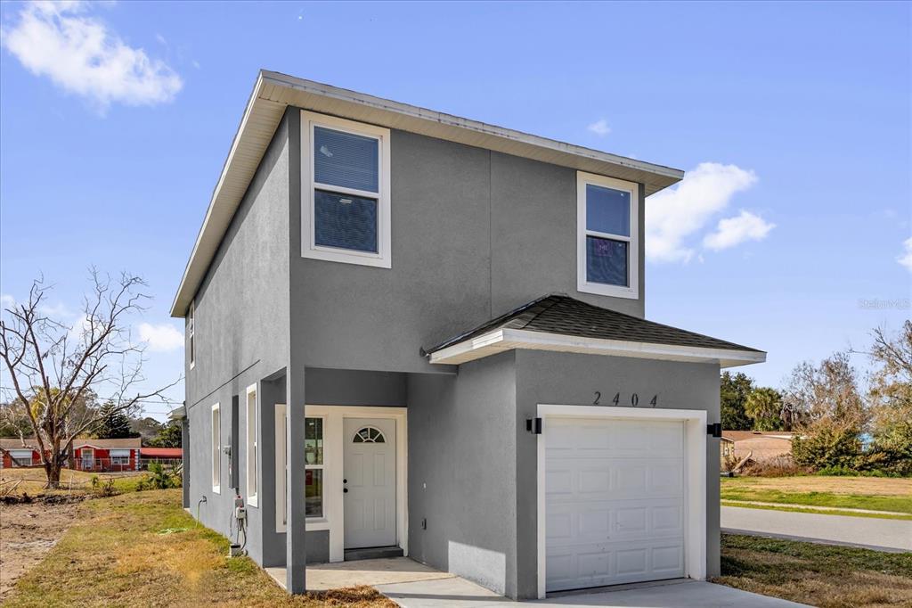 A two-story gray house with a single-car garage and a front entrance under a porch — 2404 CENTER STREET, SANFORD, FL