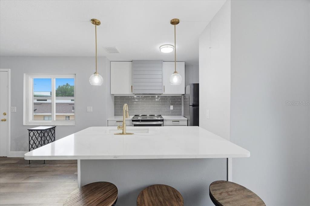 A modern kitchen features a white island, gray backsplash, and two pendant lights — 626 PAVARE COURT, WINTER HAVEN, FL