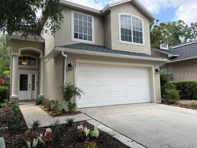A two-story suburban house with a beige exterior, a two-car garage, and a concrete driveway — 1931 LOST SPRING COURT, LONGWOOD, FL