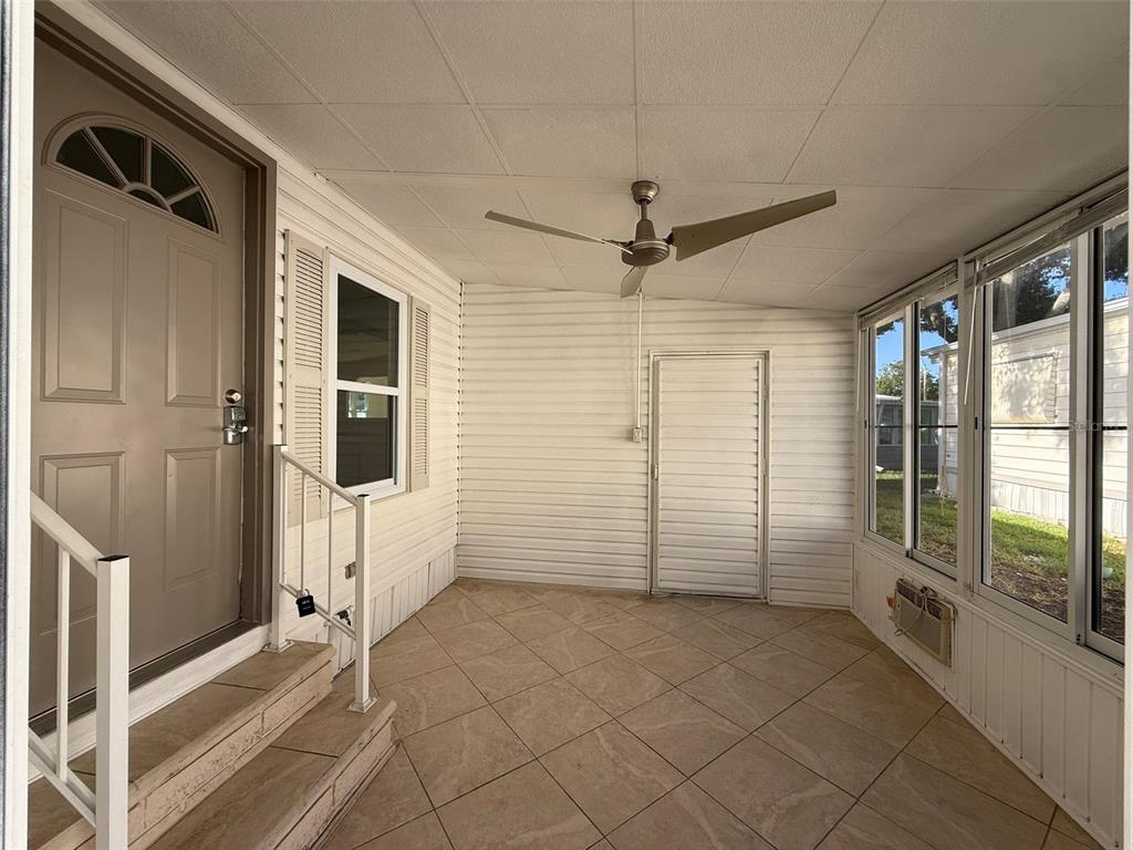 A covered porch features tiled flooring, a ceiling fan, and a door leading inside — 130 CLUBVIEW DRIVE UNIT 2, SAFETY HARBOR, FL