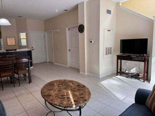 A living room with tiled floors, a marble-topped coffee table, and a television on a stand — 4778 VERO BEACH PLACE, KISSIMMEE, FL