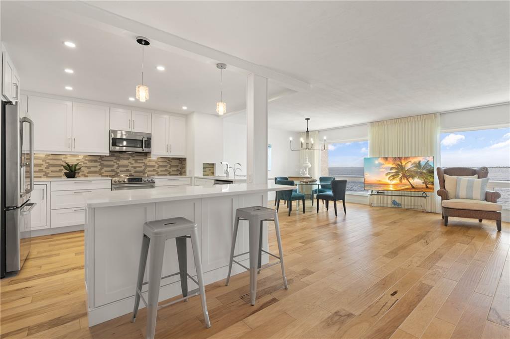 An open-concept kitchen and living area with white cabinetry, a breakfast bar, and water views — 1 COLONY POINT DRIVE UNIT 15B, PUNTA GORDA, FL