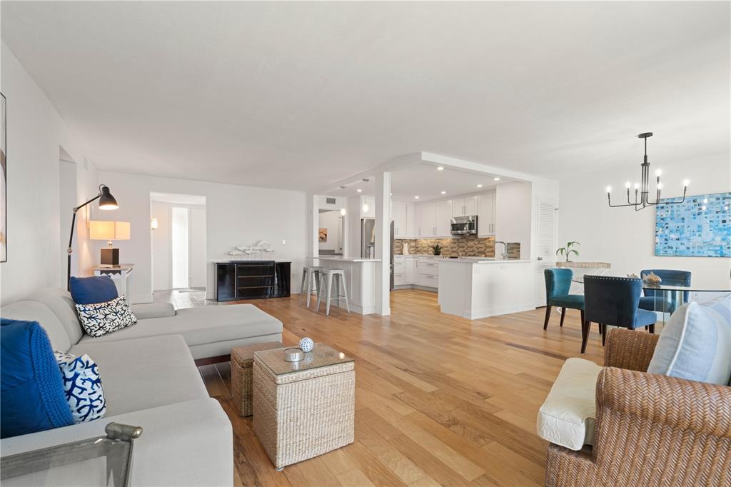 An open-concept living and dining area features hardwood floors, a white kitchen, and blue accents — 1 COLONY POINT DRIVE UNIT 15B, PUNTA GORDA, FL
