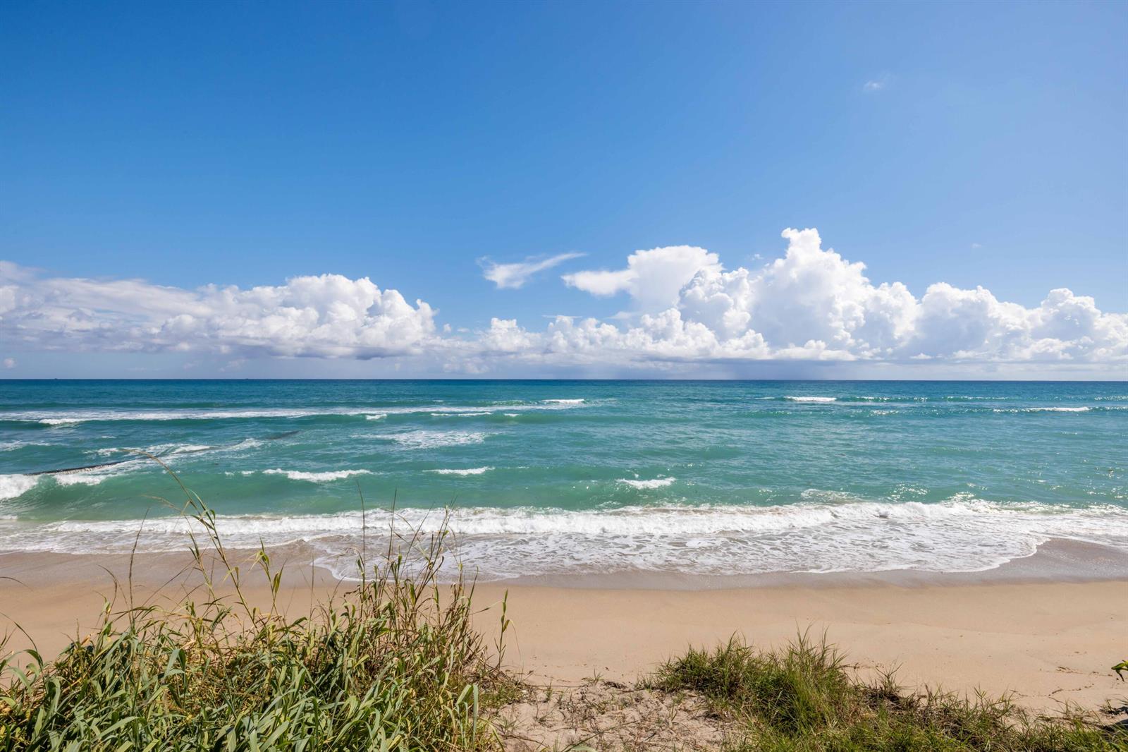 A sandy beach meets the turquoise ocean under a bright blue sky with white clouds — 1048 S Ocean Boulevard, Palm Beach FL 33480, PALM BEACH, FL
