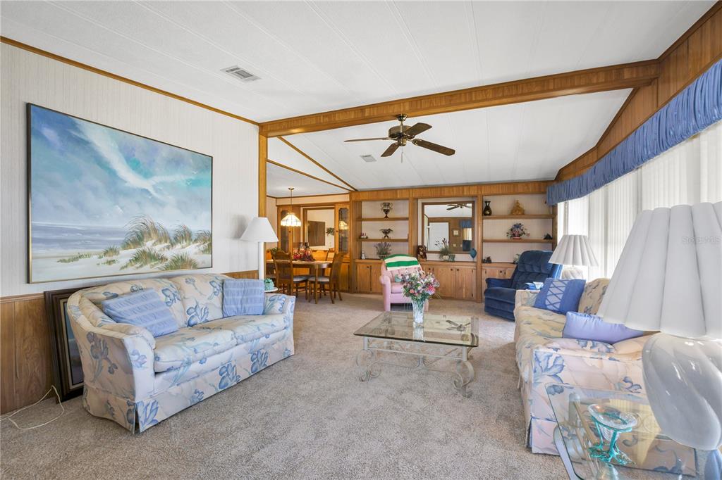 A living room features floral sofas, wood-paneled walls, built-in shelving, and a ceiling fan — 4969 FOXWOOD LAKE DRIVE, LAKELAND, FL