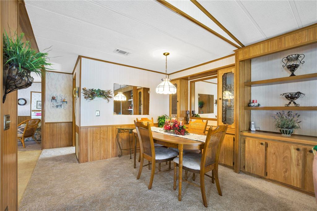 A dining room with wood paneling, a wooden table, and built-in shelving on carpeted flooring — 4969 FOXWOOD LAKE DRIVE, LAKELAND, FL