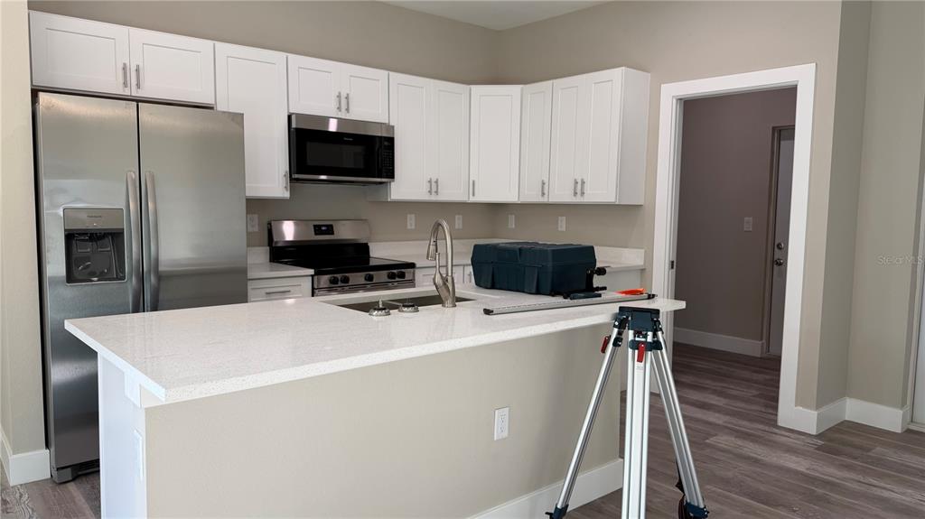 A kitchen features white cabinets, stainless steel appliances, and a white quartz-topped island — 11234 4TH AVENUE, PUNTA GORDA, FL