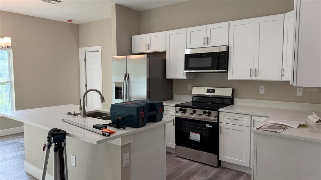 A kitchen features white cabinets, stainless steel appliances, and a central island with a sink — 11234 4TH AVENUE, PUNTA GORDA, FL