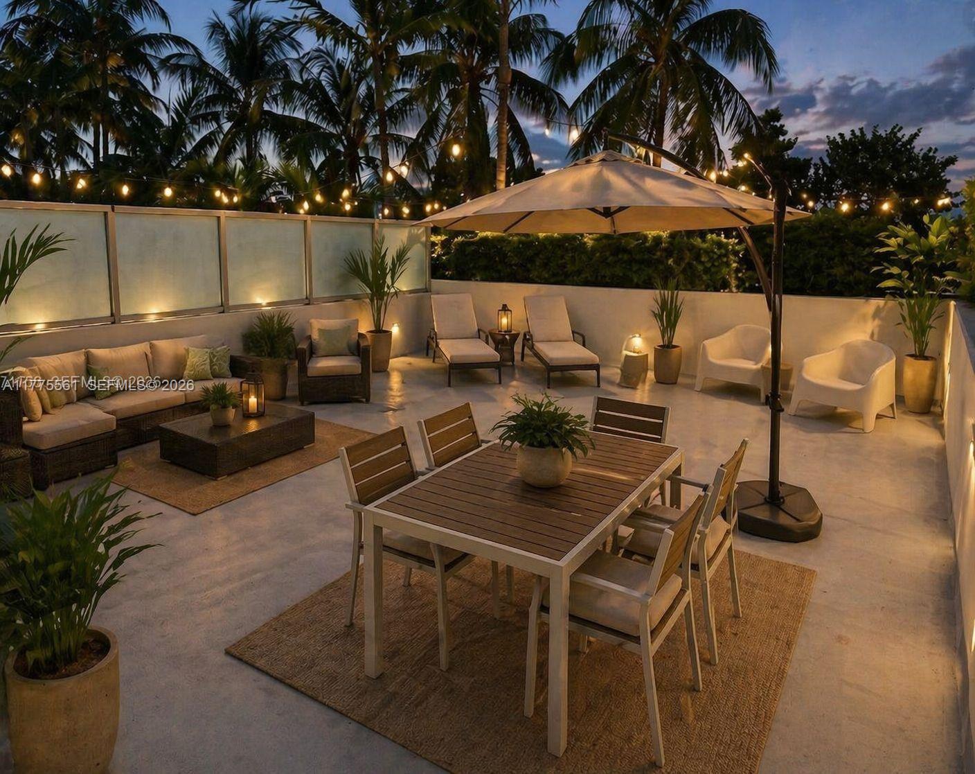 A spacious rooftop terrace features a dining set, lounge seating, an umbrella, and string lights — 2001 Meridian Ave # 309, Miami Beach FL 33139, MIAMI BEACH, FL